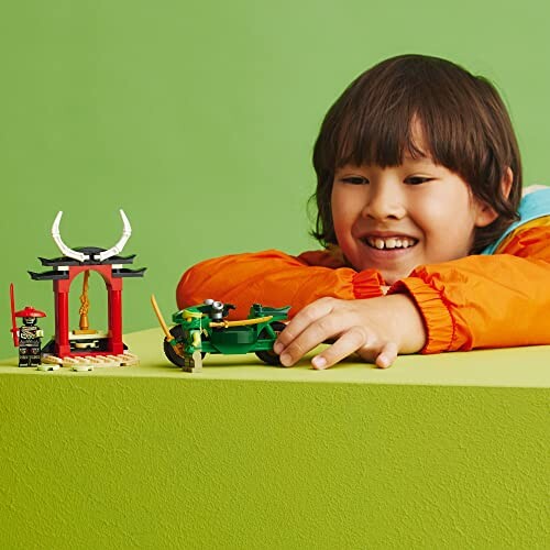 Child playing with LEGO ninja toy set on green background.