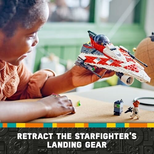 Child playing with a LEGO starfighter model.