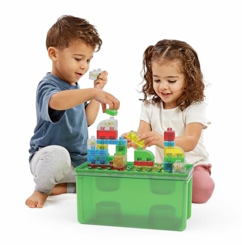 Two children playing with colorful building blocks on a green container.