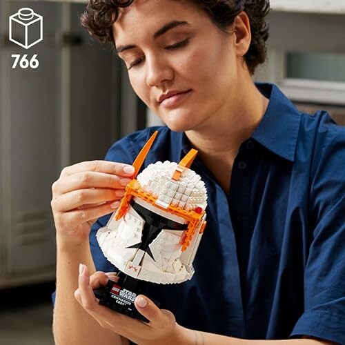 Person assembling a LEGO Star Wars helmet model.