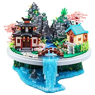 Lego diorama of a village with waterfall and cherry blossoms.