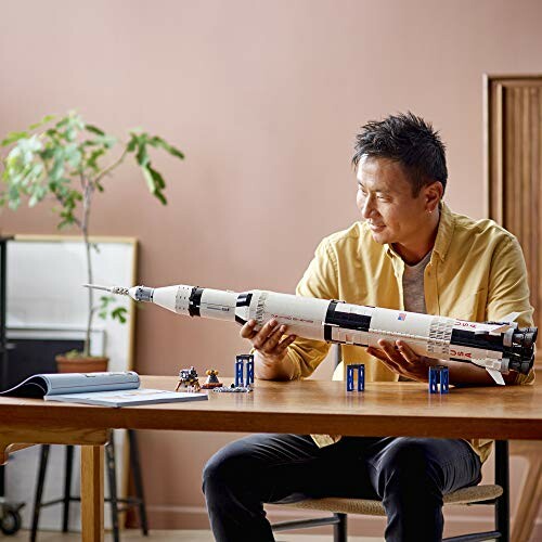 Man holding a Saturn V rocket model at a table.