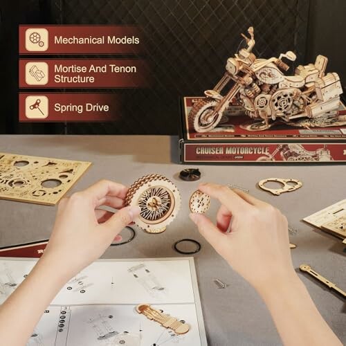 Hands assembling a mechanical motorcycle model with instructions and parts.