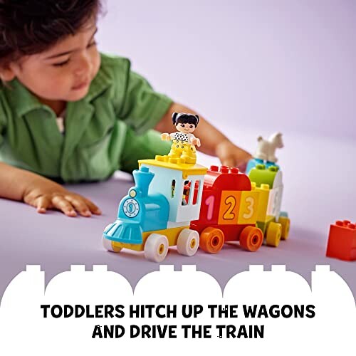 Child playing with colorful train toy set.