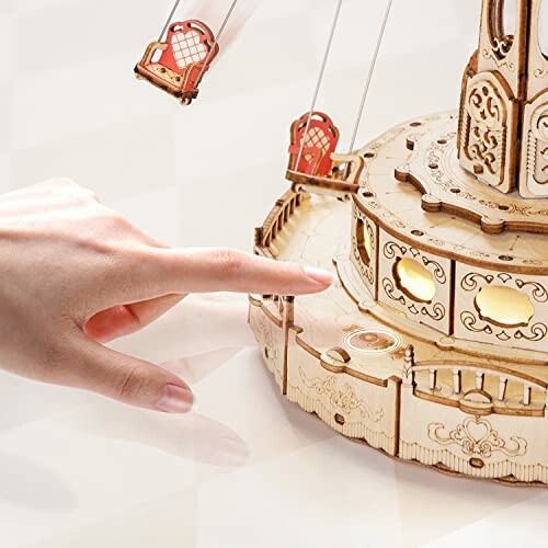 Hand touching a wooden carousel model