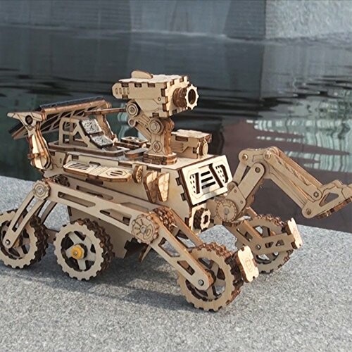 Wooden model of a rover with articulated arms and wheels.